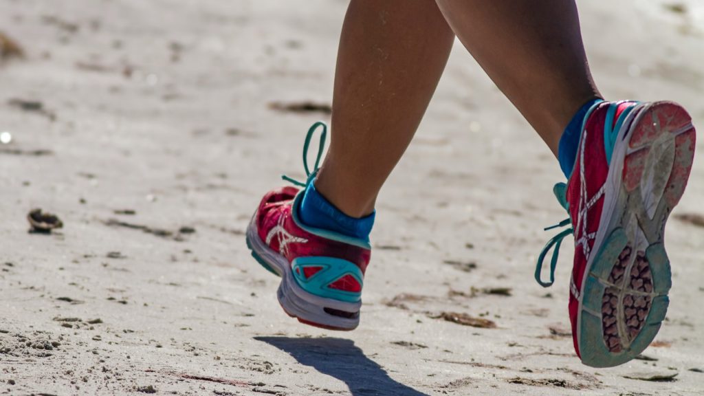 buty do biegania, buty sportowe, osoba biegnąca w butach do biegania po plaży